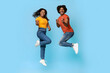 © Prostock-studio - Happy african american lovers beautiful millennial man and woman in casual celebrating success on blue studio background, jumping up and pointing at camera, full length shot, copy space