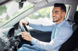 © Prostock-studio - Handsome middle-eastern businessman driving car, going on business trip, side view, copy space. Happy arab man in stylish outfit going to business meeting or to office, driving his luxury car