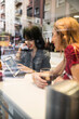 © Antonio Recena - Young people in their twenties look at a tablet inside a bar while having drinks.