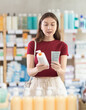 © JackF - Selective young woman client choosing cream in drugstore with large stock