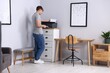 © New Africa - Man working with printer near grey wall indoors