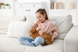 © New Africa - Girl with cute bunny on sofa at home. Space for text
