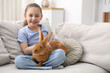 © New Africa - Girl with cute bunny on sofa at home. Space for text
