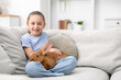 © New Africa - Girl with cute bunny on sofa at home. Space for text