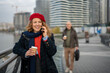 © Jelena - Woman talking on smartphone holding coffee on city promenade