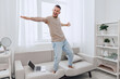 © SHOTPRIME STUDIO - Energetic man enjoying life while balancing work and personal time, celebrating emotional minimalism and authentic imperfection in a cozy home setting.