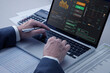 © ktasimar - Close up of a businessman's hands typing on laptop computer keyboard analysing business investment information on a desktop in an office setting