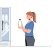 © Asbi - Woman holding milk bottle in front of refrigerator