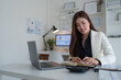 © crizzystudio - Asian businesswoman managing finances and planning work at office desk