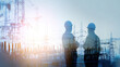 © Puthorn - Two engineers in hard hats stand silhouetted against a backdrop of electrical power lines and substation equipment on a bright day landscape.