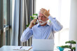 © Graphicroyalty - Stressed senior businessman on phone call at office desk. Worried mature man holding head in hand while looking at laptop. Frustrated male executive dealing with bad news or headache at work.