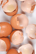 © nahhan - A macro top view showing the detailed texture and jagged edges of multiple cracked brown eggshells scattered on a white surface