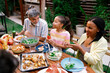 © BrightGridVisuals - Multigenerational Family Sharing Food at Outdoor Dinner Table