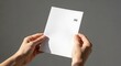 © oktaviana - Hands holding a blank A6 paper sheet for notes or presentation.