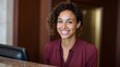 © Bussakon - A friendly woman with curly hair smiles warmly at a hotel reception desk embodying hospitality