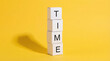 © Ajay - Time concept with stacked white cubes spelling word time on bright yellow background symbolizing schedule deadline planning and productivity.