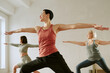 © AnnaStills - Three Caucasian women practicing yoga in studio, standing in warrior pose with arms extended, including two middle aged women and one young adult woman focusing on balance and flexibility