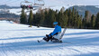 © Alex - A wheelchair user makes a turn while skiing down a mountain