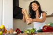 © sutulastock - Young woman preparing and seasoning a fresh vegetable salad in a modern kitchen. Full lifestyle series on clean eating, wellness, and healthy food preparation.