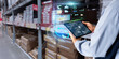 © panuwat - Business Logistics warehouse management system technology concept.Man hands using tablet on blurred warehouse as background