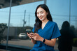 © PaeGAG - Asian doctor smiling while using smartphone outside hospital