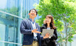 © Trickster* - 屋外でタブレットを使い提案するビジネス男女, Business team making a proposal with a tablet outdoors