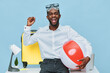 © SHOTPRIME STUDIO - Smiling man with dark skin celebrating summer vacation, wearing glasses and casual white shirt, holding a large beach ball, surrounded by travel and leisure items in bright studio setting. People