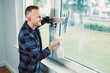 © DSMT - Man cleans window with spray bottle and squeegee in modern home setting during daytime