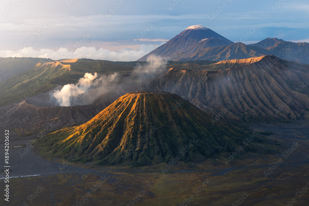 Aerial view of majestic Mount Bromo shrouded in ethereal mists, its volcanic peak contrasting with the rugged terrain, East Java, Indonesia.