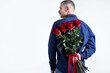 © New Africa - Valentine's day celebration. Man hiding beautiful bouquet of red roses behind his back on white background, space for text