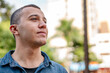© Nexa - Thoughtful young man in a denim shirt looking into the distance outdoors in a city park