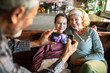 © Geber86 - Grandfather photographing granddaughter and grandmother with face masks at home