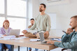 © Pixel-Shot - Funny young man meditating on table with his colleagues in office