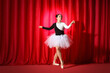 © Pixel-Shot - Young ballerina dancing near red curtains