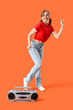 © Pixel-Shot - Young woman with boombox dancing on orange background