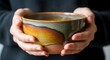 © Husein - Hands holding ceramic bowl warm colors and textured surface
