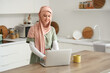 © Pixel-Shot - Beautiful young Muslim woman in hijab with modern laptop and cup of hot tea in kitchen