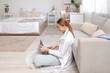 © Pixel-Shot - Female medical student in eyeglasses studying with modern laptop on floor at home