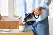 © Pixel-Shot - Handsome young man pouring hot espresso from coffee pot into cup in office, closeup