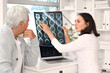 © Pixel-Shot - Female doctor showing x-ray scan to senior patient in medical office