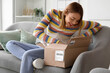 © Pixel-Shot - Young woman opening parcel at home