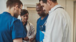 © Flamingo Images - A diverse team of four doctors stands together in a hospital, deeply focused as they review medical documents. They all share a serious expression, reflecting the gravity of their discussion.