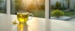 © CreativeBro - Glass tea cup filled with green tea, ginger, and turmeric placed near a sunny window