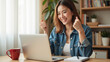 © Oran - Happy woman celebrating success while using laptop at home, showing excitement and joy