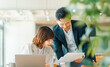 © Trickster* - オフィスで資料を確認する上司と部下の打ち合わせシーン, Manager and junior staff reviewing documents together in office
