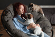 © Tatyana Gladskih - Cheerful Young Woman sitting on Couch with her pets Dog and Cat at home