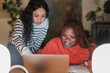 © Studio Marmellata - Two young women collaborate on a laptop, one pointing at the screen while the other smiles, engaged in learning or work.