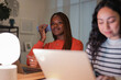 © Studio Marmellata - A young woman talks on her phone while working on a laptop, with a colleague focused on her own computer in the foreground.