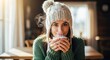 © MT Studio - A woman in a cozy knit hat and green sweater enjoys a warm beverage on a chilly day