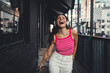 © BullRun - Carefree woman laughs in headphones with raised arms, enjoying music and movement in a bright outdoor scene. Expressive pose captures liberation through sound and wearable technology.